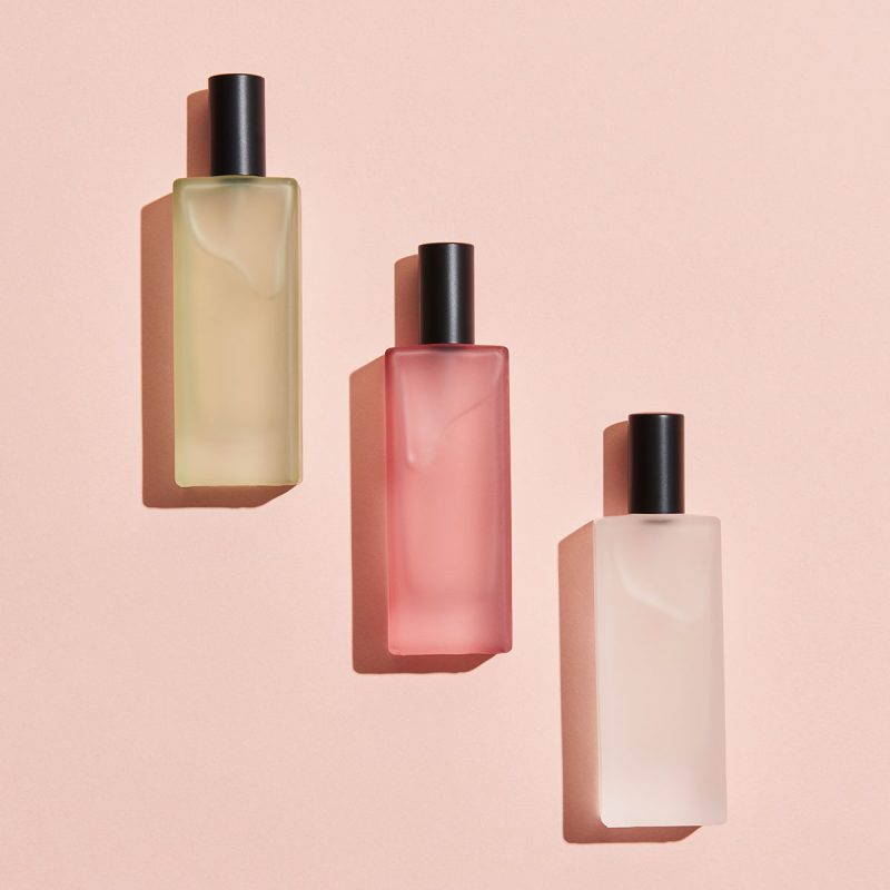 Three bottles of cosmetics are shown on a pink background.