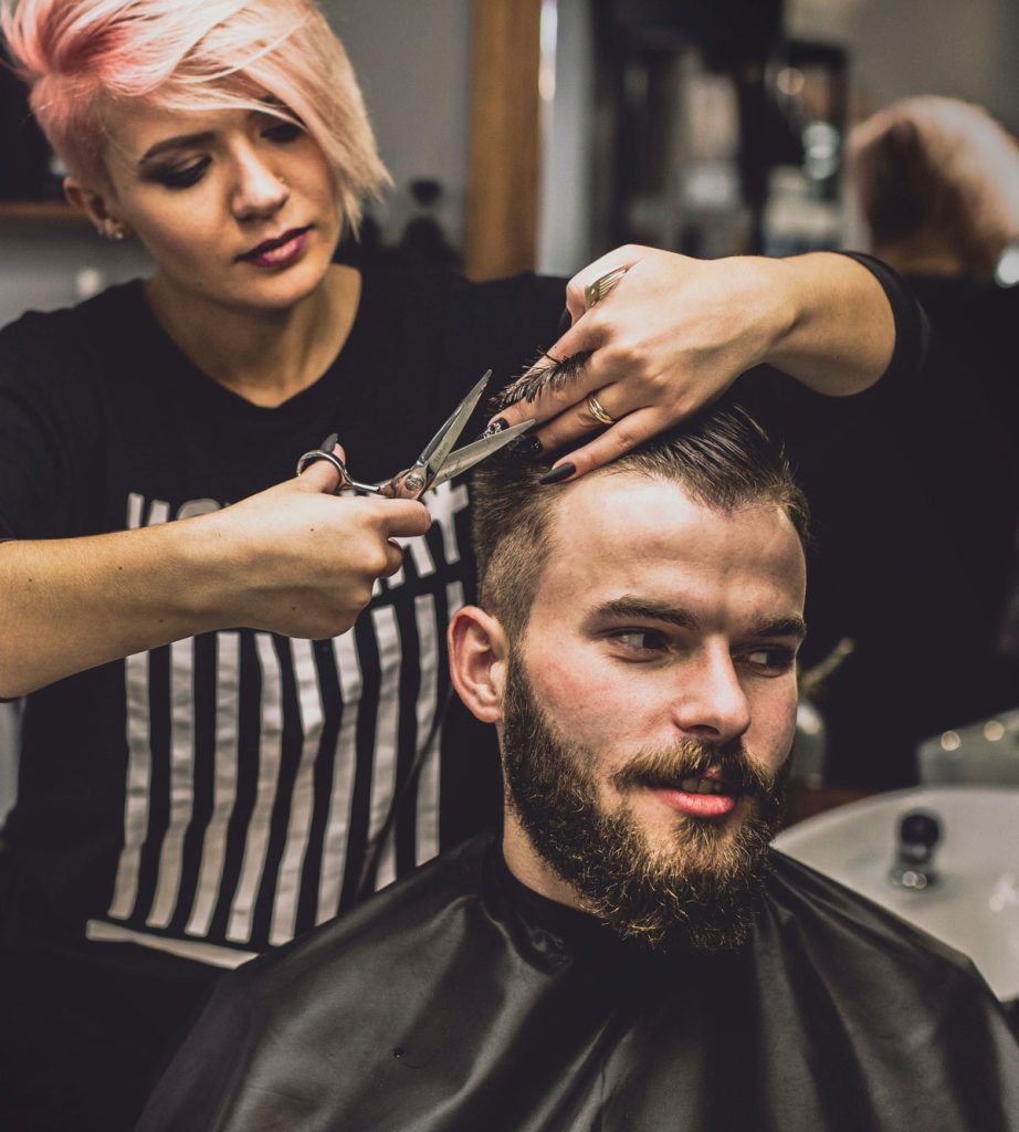 A woman cutting the hair of a man.