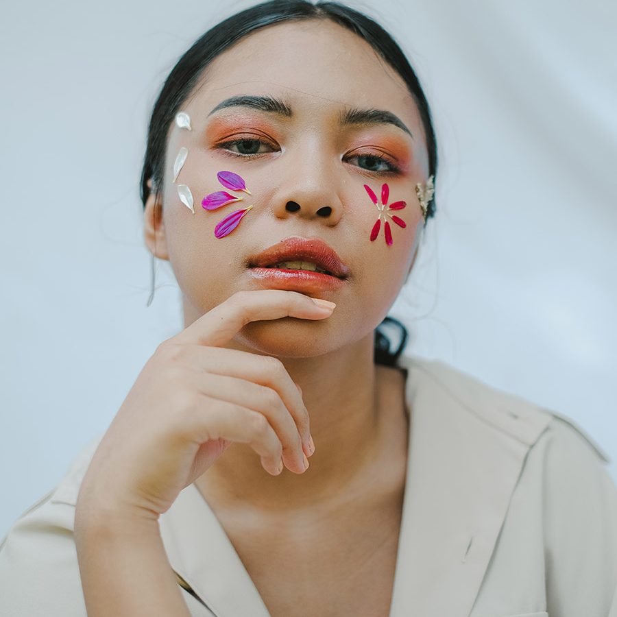 A woman with stickers on her face and hand near her cheek.