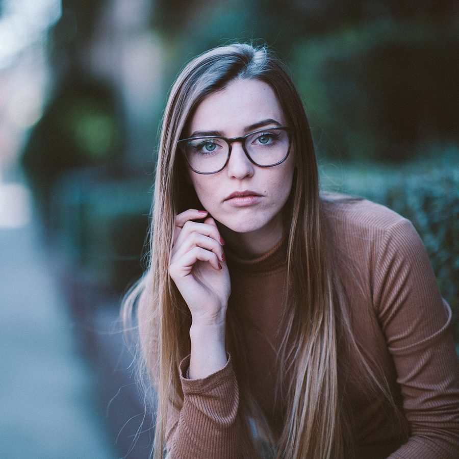 A woman with glasses sitting on the ground