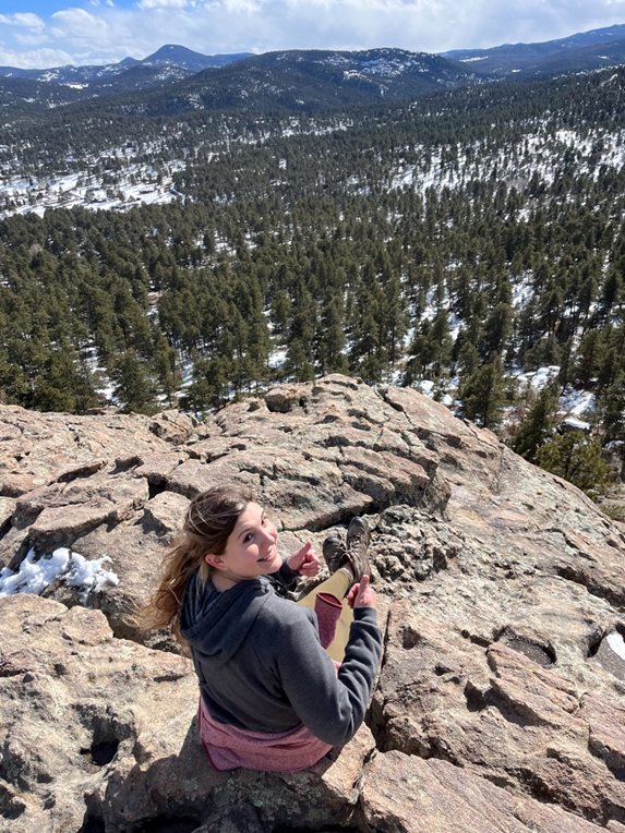 A woman holding a guitar on top of a mountain.